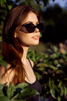 pretty woman in sunglasses in summer outdoors green leaves. High quality photo