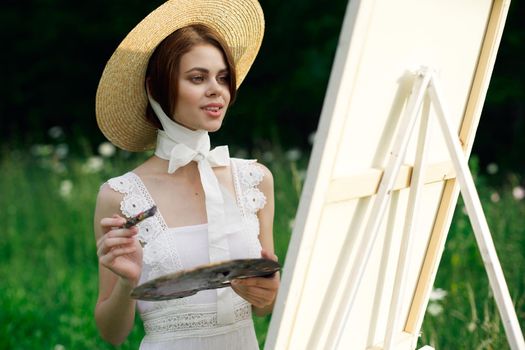 Woman in white dress artist easel painting nature landscape. High quality photo