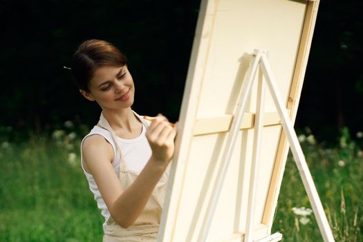 woman artist paints a picture near easel outdoors landscape creative. High quality photo