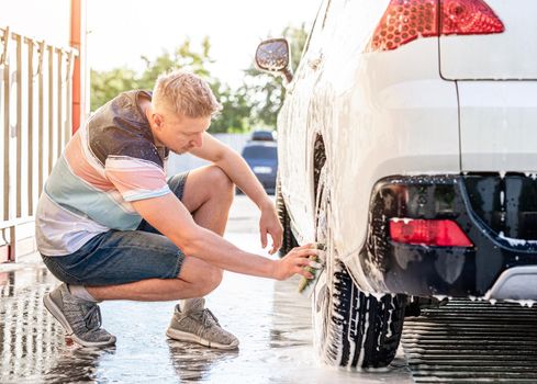 Man is washing car using sponge at self service car wash