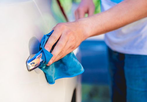 Hand with microfiber rag polishing car handle