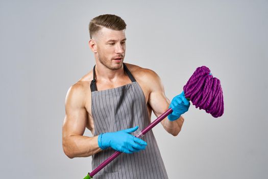 man in apron with mop in hand posing housework. High quality photo