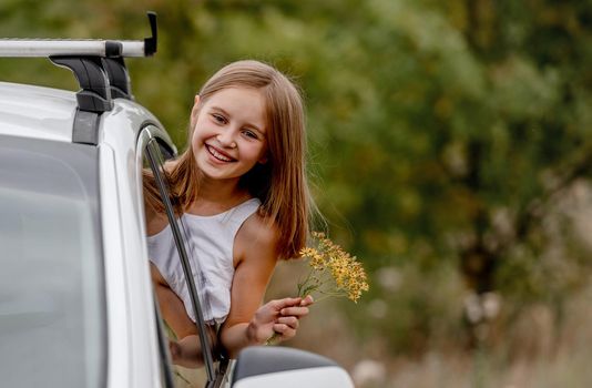 Preteen girl looking from car window and smiling. Cute child kid during journey in vihicle at nature