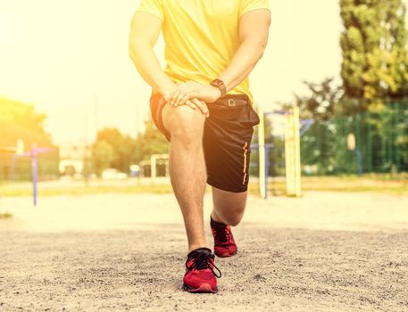 Man in sport uniform doing lunges during street training, cropped image