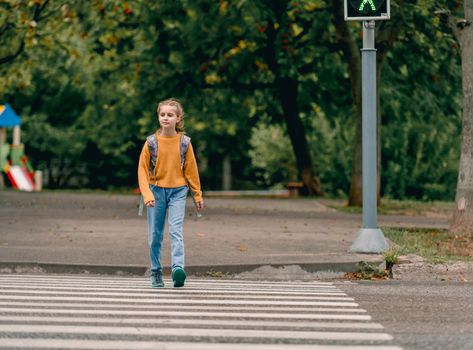 School girl with backpack outdoors walking. Pretty female child kid after lessons going home