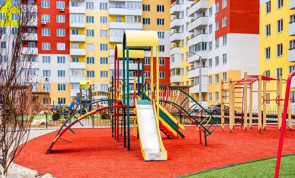 Public colorful children playground for kids activities with new houses on background