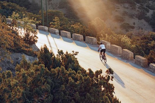 Professional man cyclist on a mountain road at sunrise