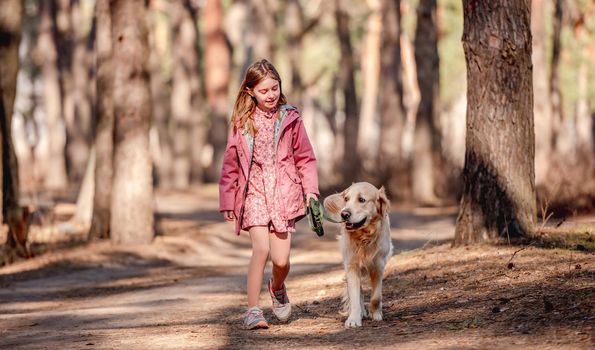 Little beautiful girl walking with golden retriever dog on the nature