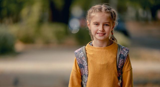 Preteen school girl with backpack looking at camera. Pretty pupil female kid portrait outdoors after education class in autumn park