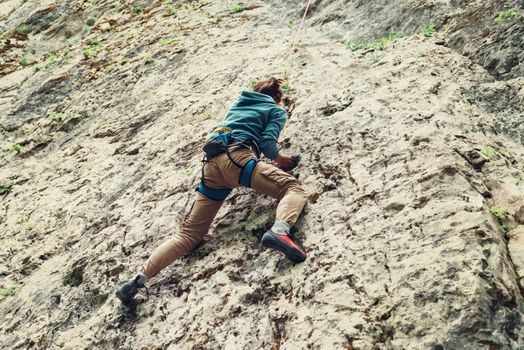 Active young woman climbing on rock outdoor in summer