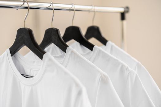 Row of white t-shirts on hangers hanging on rack