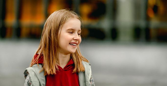 Pretty girl kid autumn portrait outdoors. Beautiful female child looking back and smiling