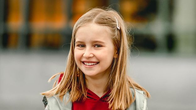 Pretty girl kid autumn portrait outdoors. Preteen female child looking at camera and smiling
