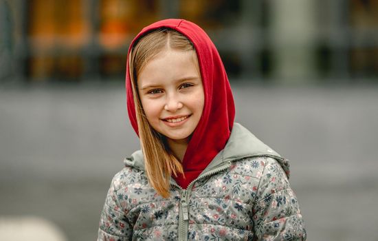 Preteen girl wearing hood at the street at autumn. Pretty female kid portrait outdoors