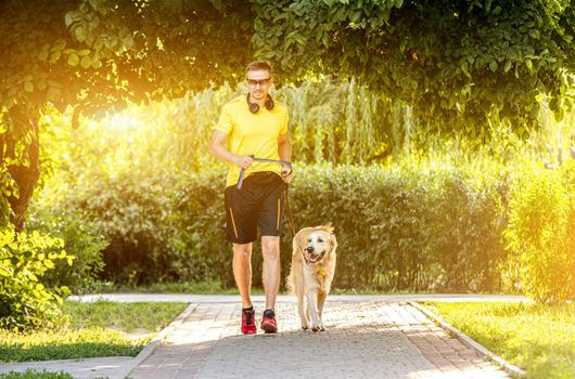 Young man jogging in park with golden retriever dog