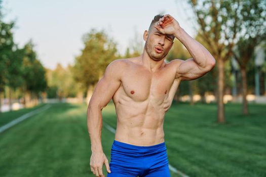 sporty man with pumped up body in park workout exercise. High quality photo