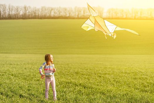 Beautiful little girl with flying kite on sunny field