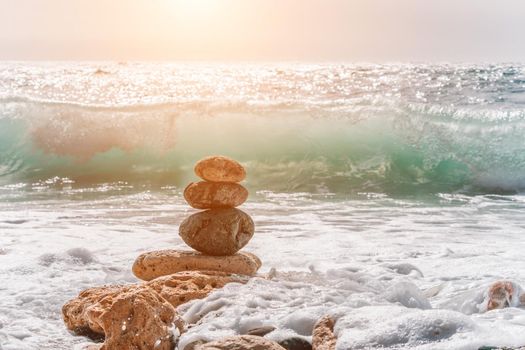 Balanced Pebbles Pyramid on the Beach on Sunny Day and Clear Sky at Sunset. Blue Sea on Background Selective focus, zen stones on sea beach, meditation, spa, harmony, calm, balance concept.