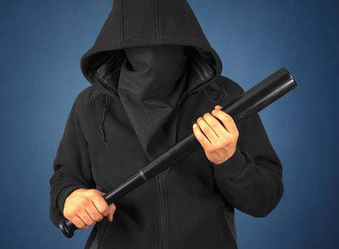 Bandit man in the mask holds bat on a dark background