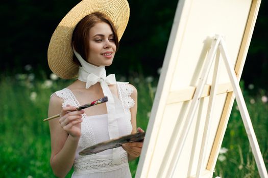 Woman in white dress artist easel painting nature landscape. High quality photo