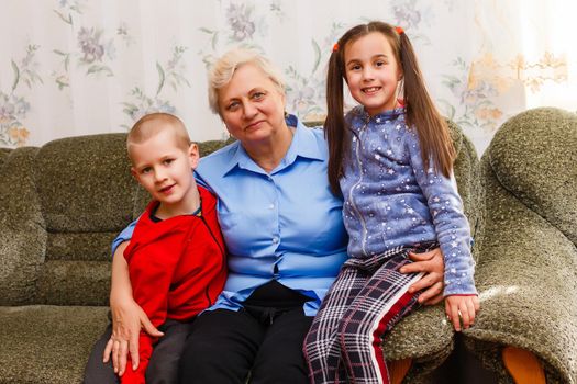 Grown up adult smiling grandchildren embraces elderly grandmother glad to see missing her, visit of loving relatives enjoy communication, cuddle as symbol of connection, love and support concept