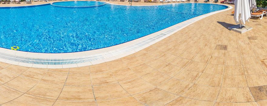 Pool with pure blue water background. Top view of swimming pool and floor texture. Panorama of pool bottom with tile pattern and transparent water. Summer travel and vacation background concept.