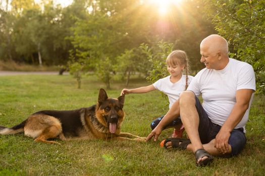Grandfather with granddaughter and a dog in the garden