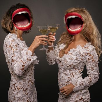 Collage of open mouth instead of a woman's head. Two beautiful young women girlfriends celebrate the holiday with martini glasses. Gossip concept