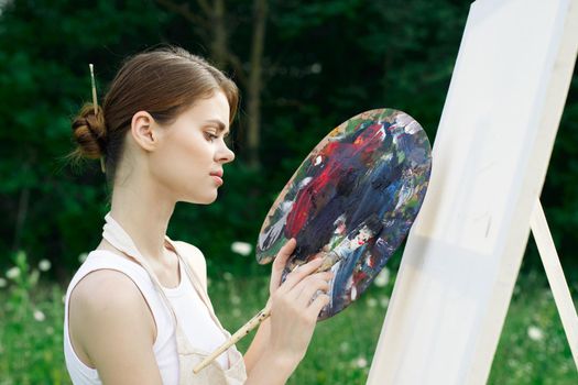 woman artist paints palette easel nature drawing. High quality photo