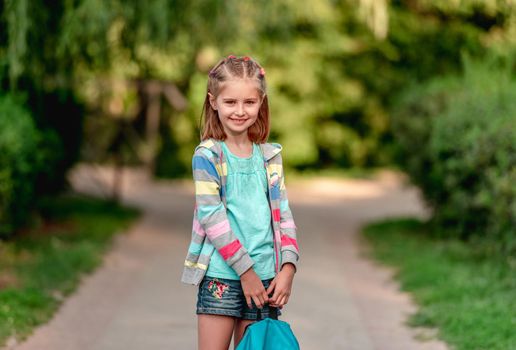 Portrait of little girl in mask running outdoors after schooling