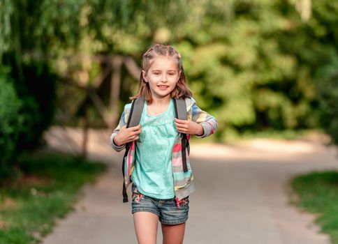 School girl walking through park after school