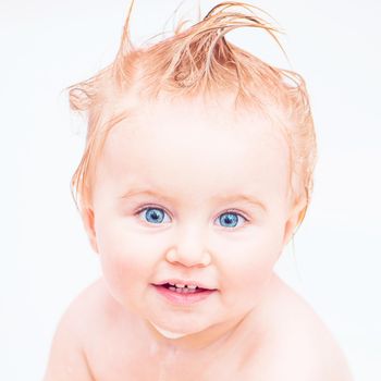 cute 1 year-old girl bathes in a bath with foam closeup
