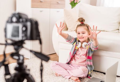 Happy smiling little girl recording video with headphones on