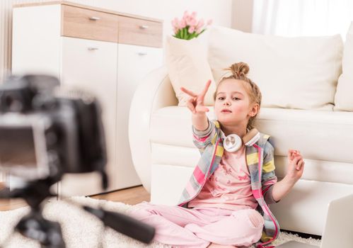 Happy smiling little girl recording video with headphones on