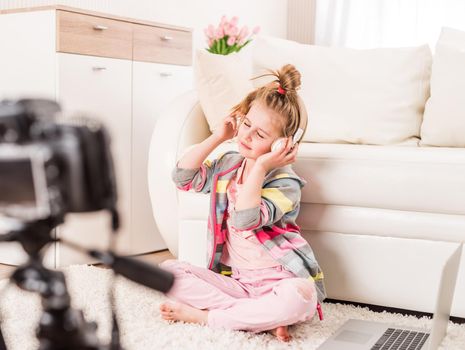 Happy smiling little girl recording video with headphones on
