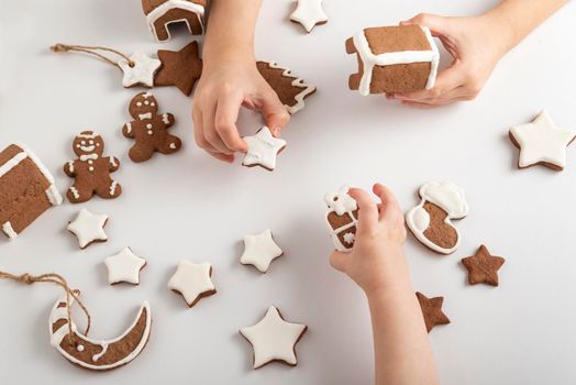 Children's hands and sugar glazed gingerbread cookies on white background, top view