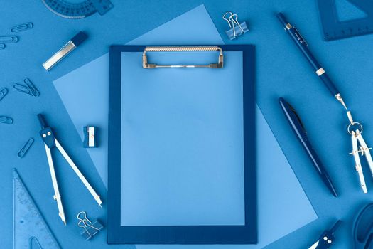 Classic blue colored top view photo of scattered stationery. Close up.