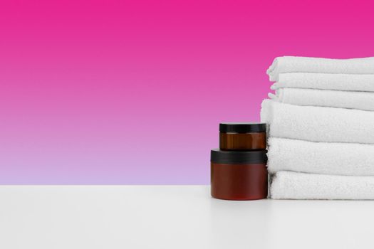 Pile of towels, bottles with shampoo on white table isolated