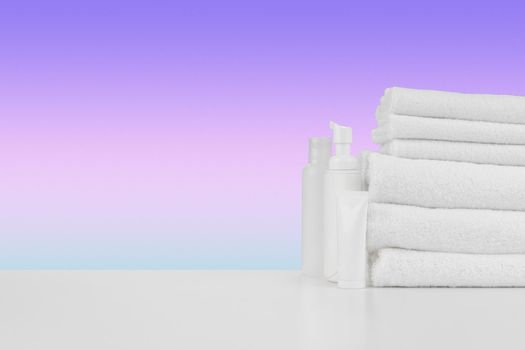 Pile of towels, bottles with shampoo on white table isolated