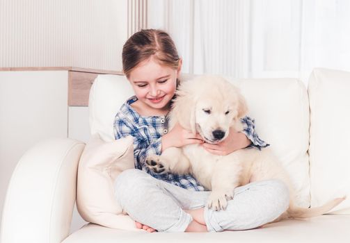 Little girl stroking fluffy puppy on sofa