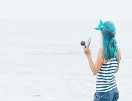 Tourist young woman with photo camera looking at sea.