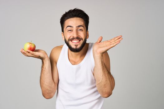 a man in a white t-shirt fresh fruit apples vitamins light background. High quality photo