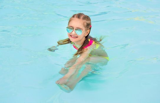 Happy child with sunglasses in swimming pool