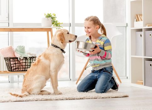 Beautiful little girl feeding cute dog indoors
