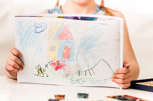 Little girl showing her beatiful drawing, made with dry pastel