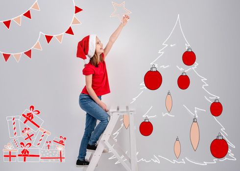Little girl in santa hat decorating christmas tree sketch with drawn top star on white wall background