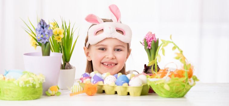 Happy smiling child peals from behind traditional and beatiful Easter decorations, isolated on white background