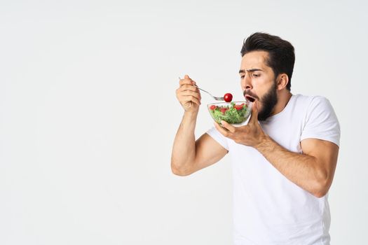 a man in a white t-shirt in a plate with salad a snack healthy food. High quality photo