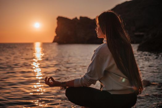 Young woman in swimsuit with long hair practicing stretching outdoors on yoga mat by the sea on a sunny day. Women's yoga fitness pilates routine. Healthy lifestyle, harmony and meditation concept.