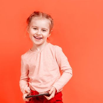Smiling small girl kid holding mobile phone over rose background